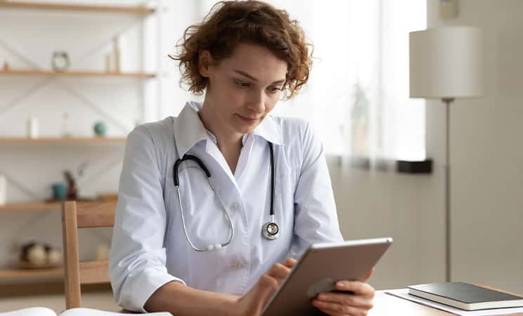 Female nurse in front of ipad looking at patient record