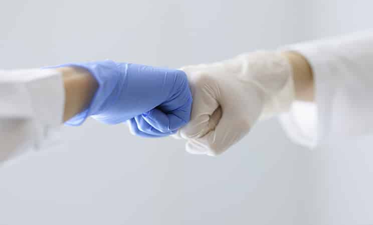 fistbump med kirurgiska handskar vit och blå som gör ett samtycke