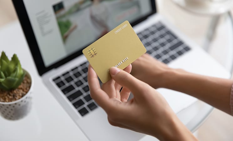 kreditkort hand framför en datorskärm som har ett bokningssytem