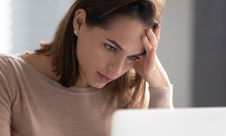 Kvinna framför dator som ser bekymrad ut